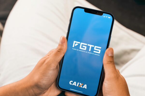 Pessoa segurando celular com a tela do aplicativo FGTS da Caixa aberta